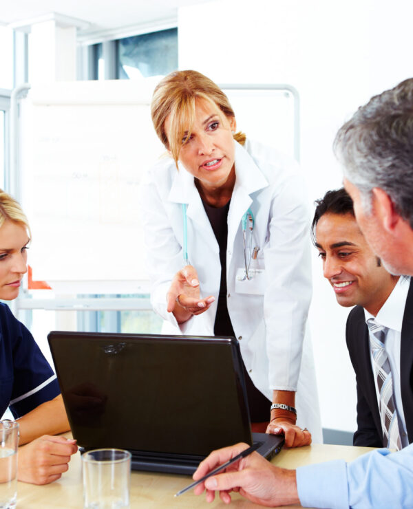 Confident female doctor showing laptop to colleagues